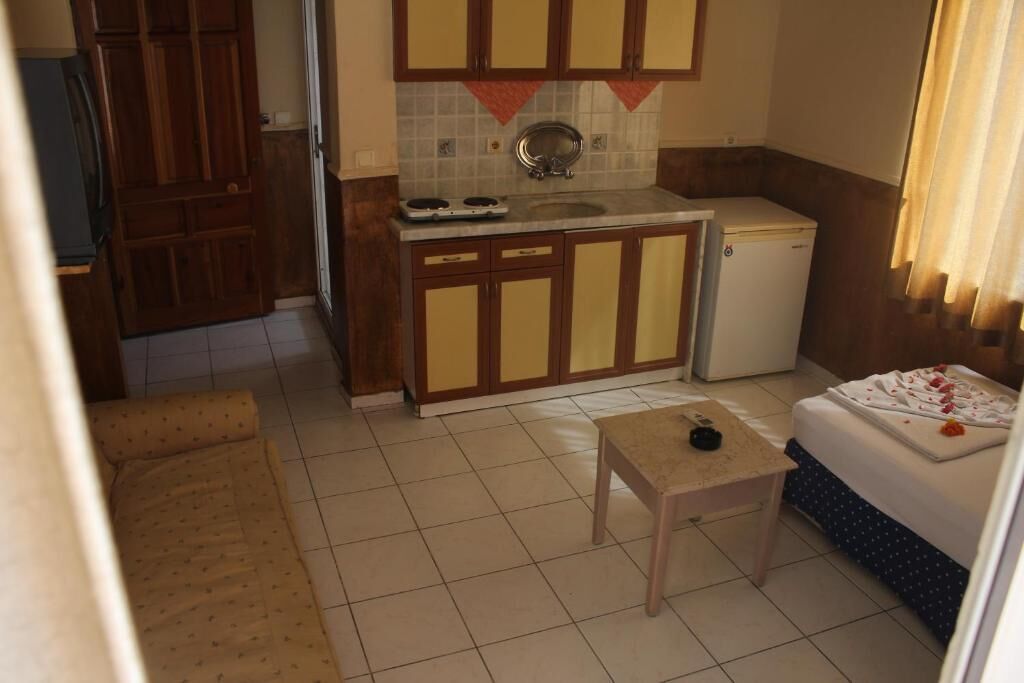 Een kleine keuken met een koelkast, een spoelbak en een tafeltje.