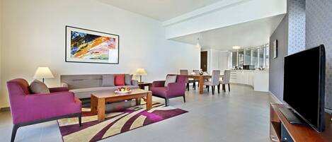 A modern living room with a sofa, armchairs, a coffee table, and a flat-screen TV.