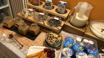 Un buffet con diversi cibi e bevande, tra cui barattoli di conserve, una ciotola di frutta secca e vasetti di yogurt.