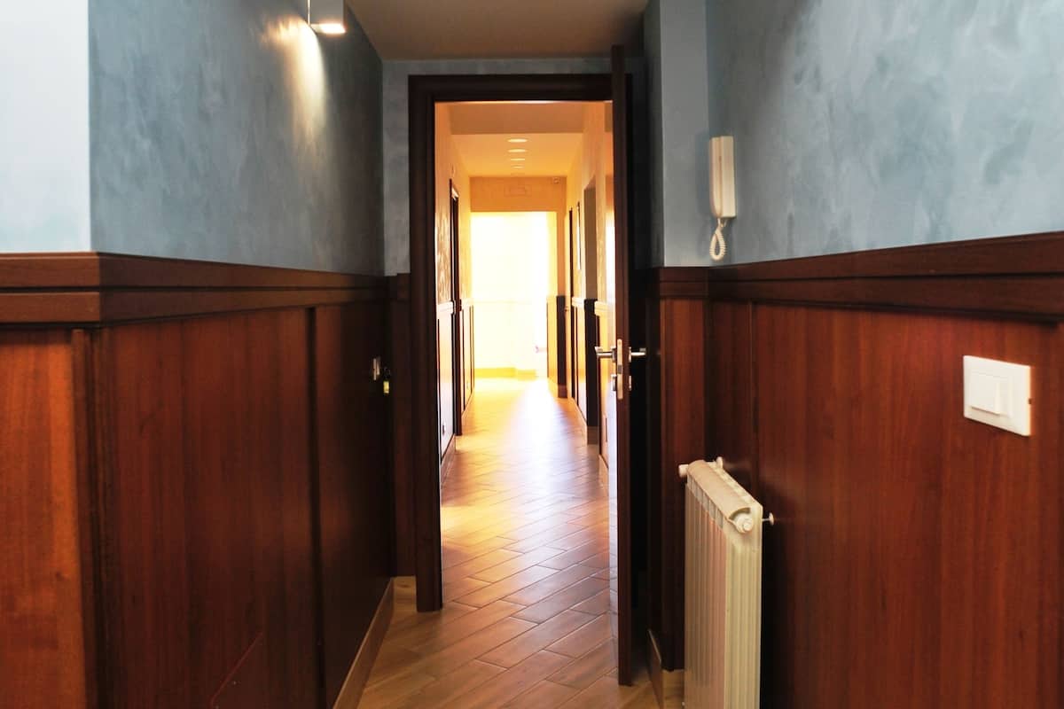 A hallway with wooden paneling, a radiator, and a light fixture on the wall.