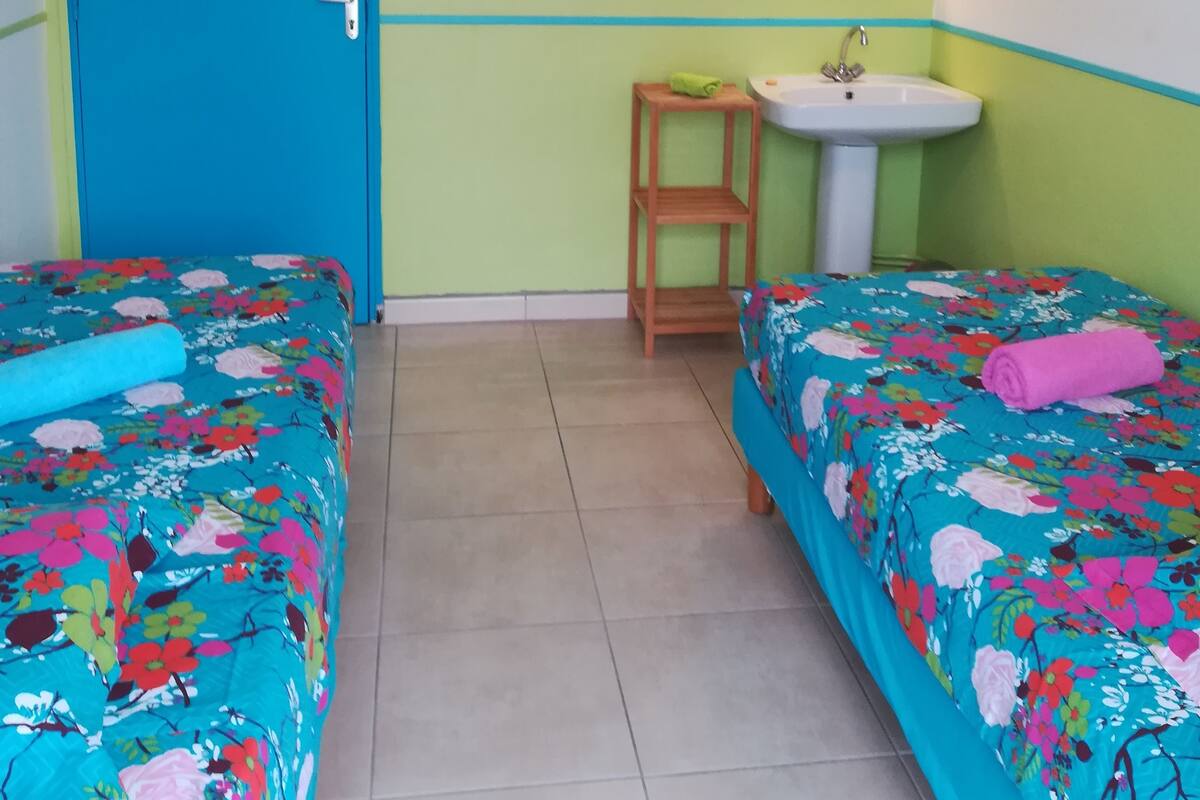 A room with two beds, a sink, and a door.