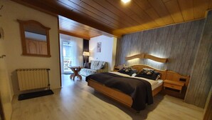 A bedroom with a wooden bed, a radiator, a table, and a sofa. - Pension Robin Hood (Willingen)