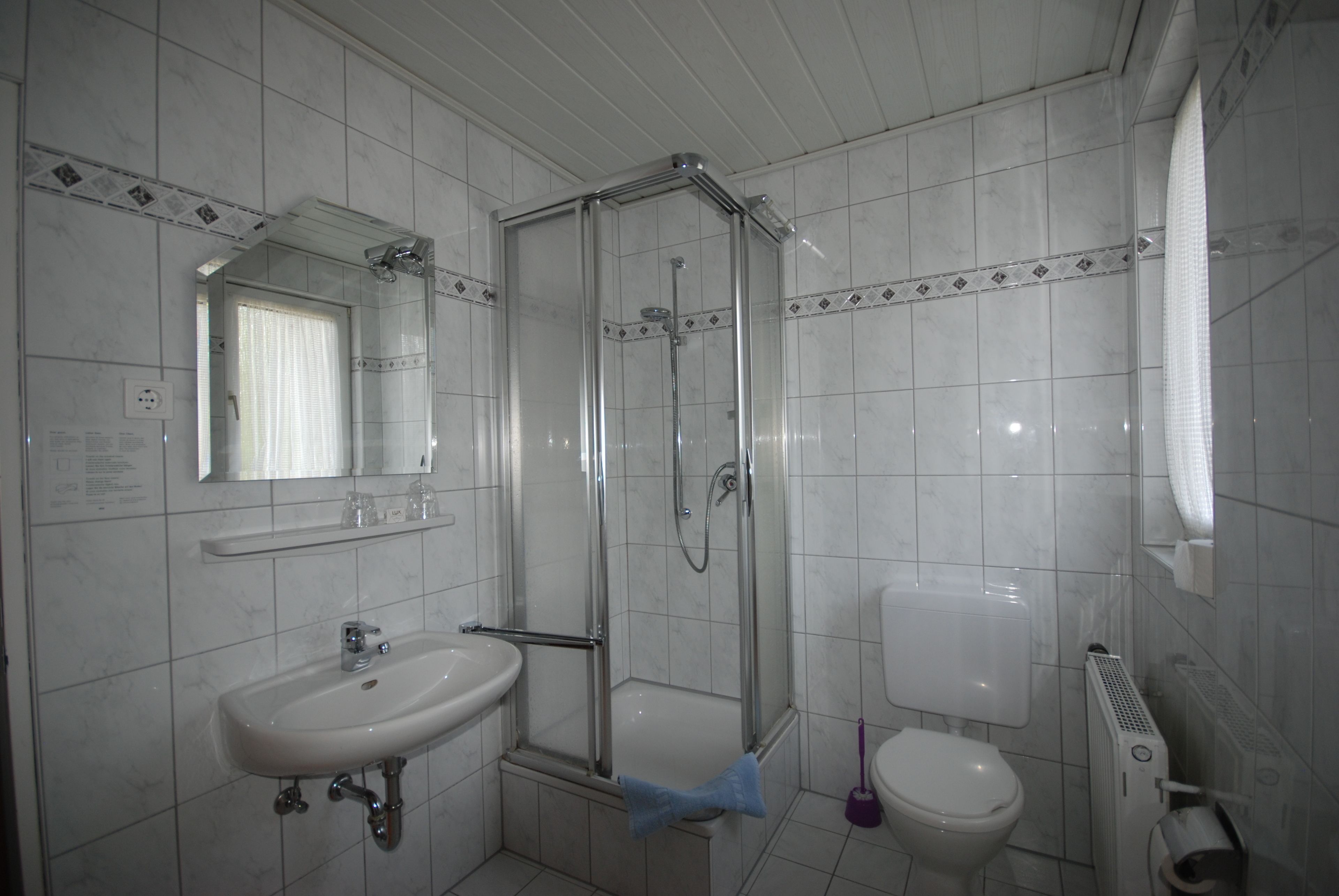 Un baño con ducha de vidrio, lavamanos, inodoro y espejo.