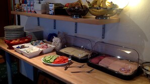 A buffet table with various food items and utensils. - Pension Robin Hood (Willingen)