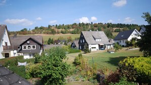 A residential area with houses, a grassy field, and a hilly background. - Pension Robin Hood (Willingen)