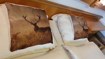A hotel room with two beds, each with a pillow featuring a deer silhouette.