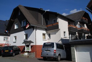 Un immeuble résidentiel de deux étages avec un fourgon gris garé devant.