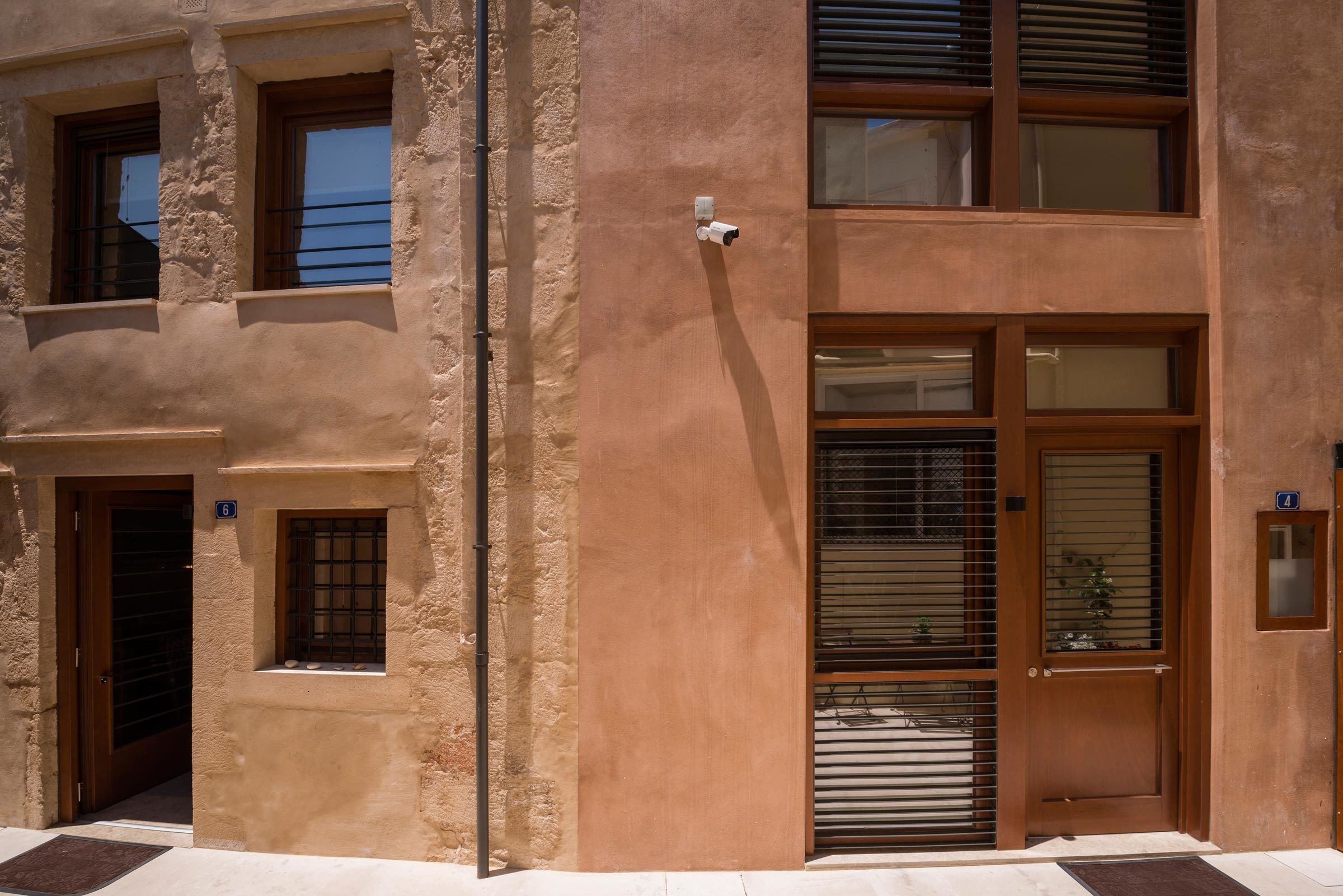 A building with a beige facade, a wooden door, and a window with blinds.