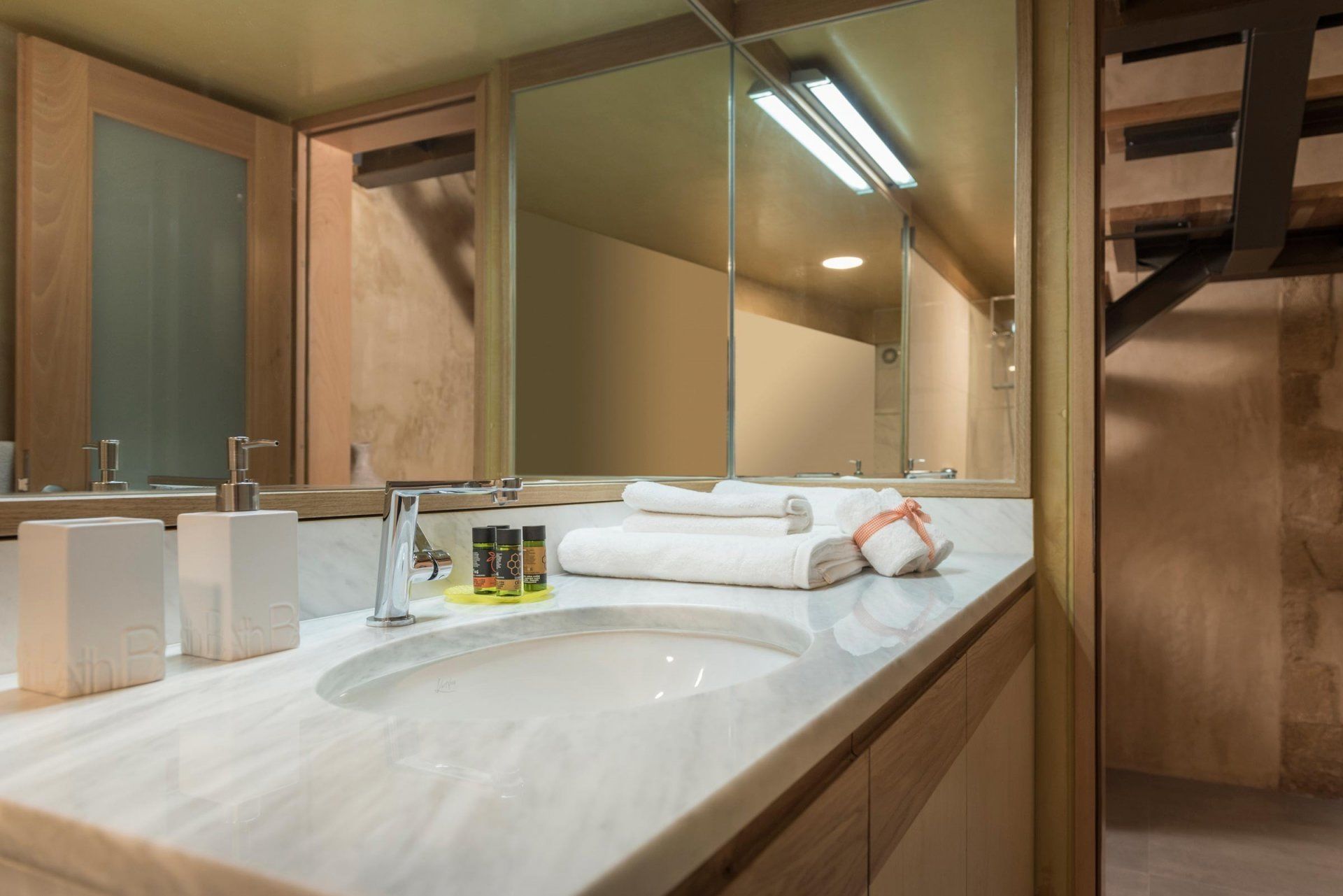 A bathroom with a large mirror, a sink, and two bottles of toiletries.