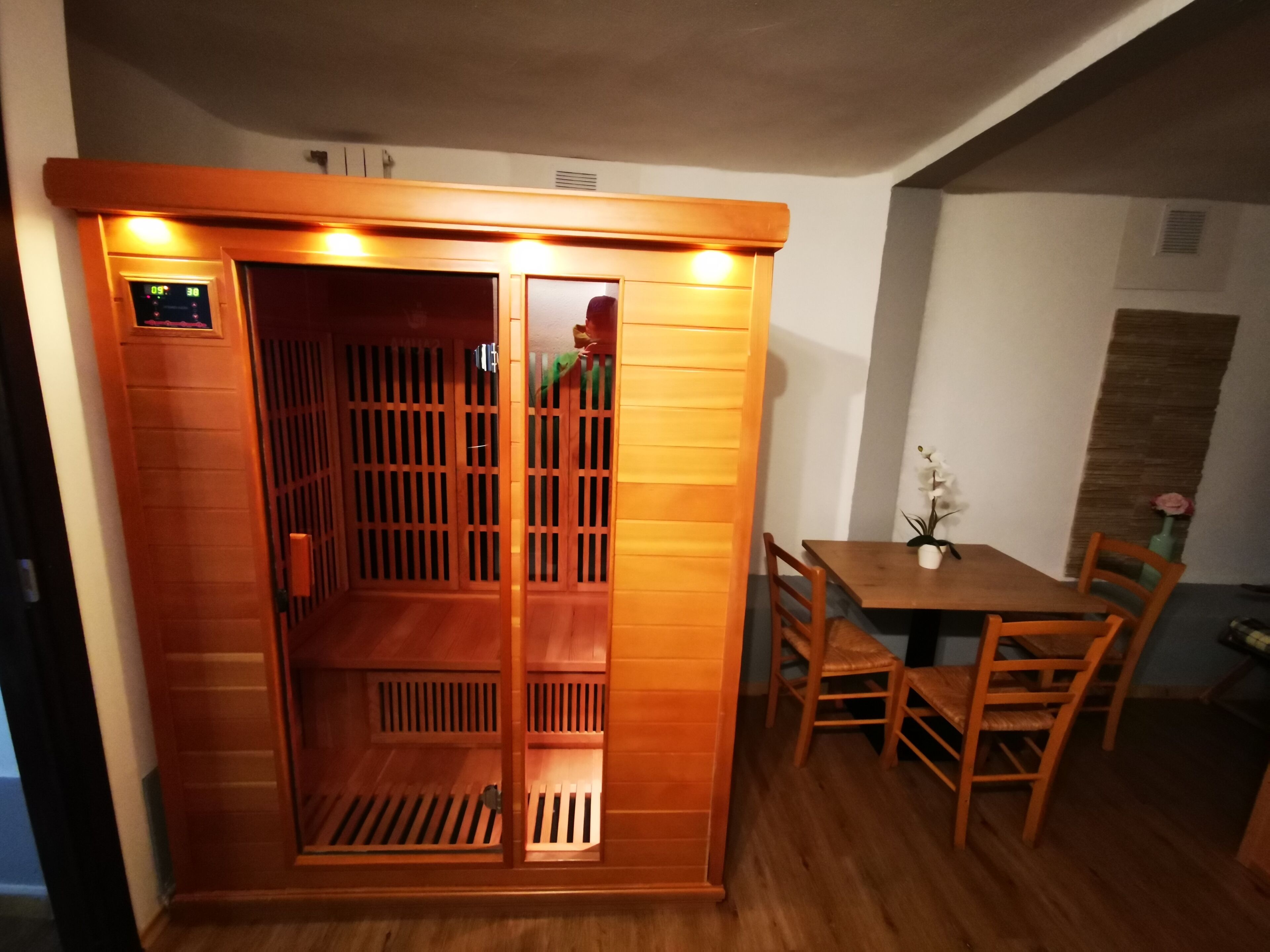 A sauna room with wooden panels and a control panel.