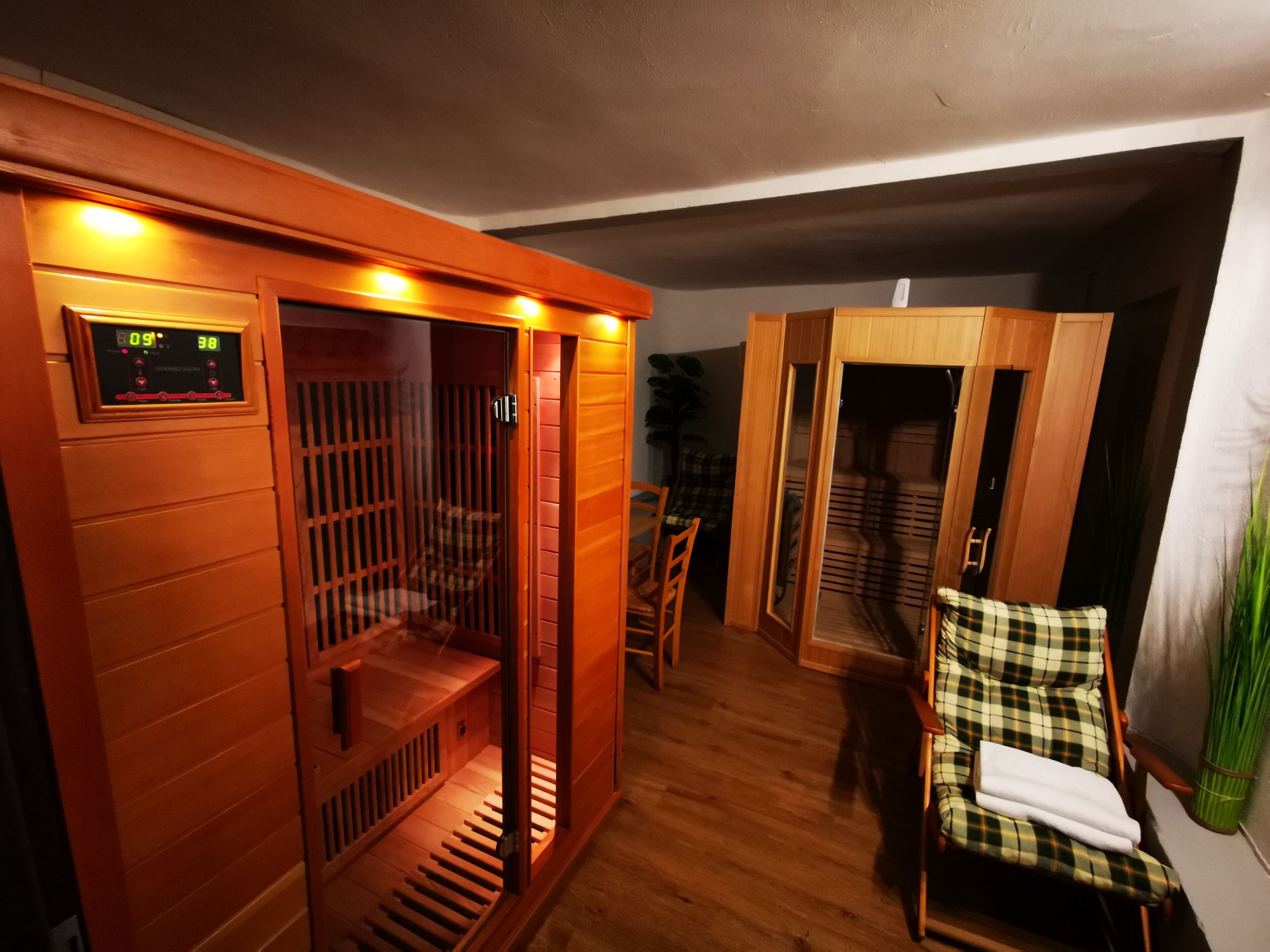 Een sauna met houten banken en een digitaal bedieningspaneel.