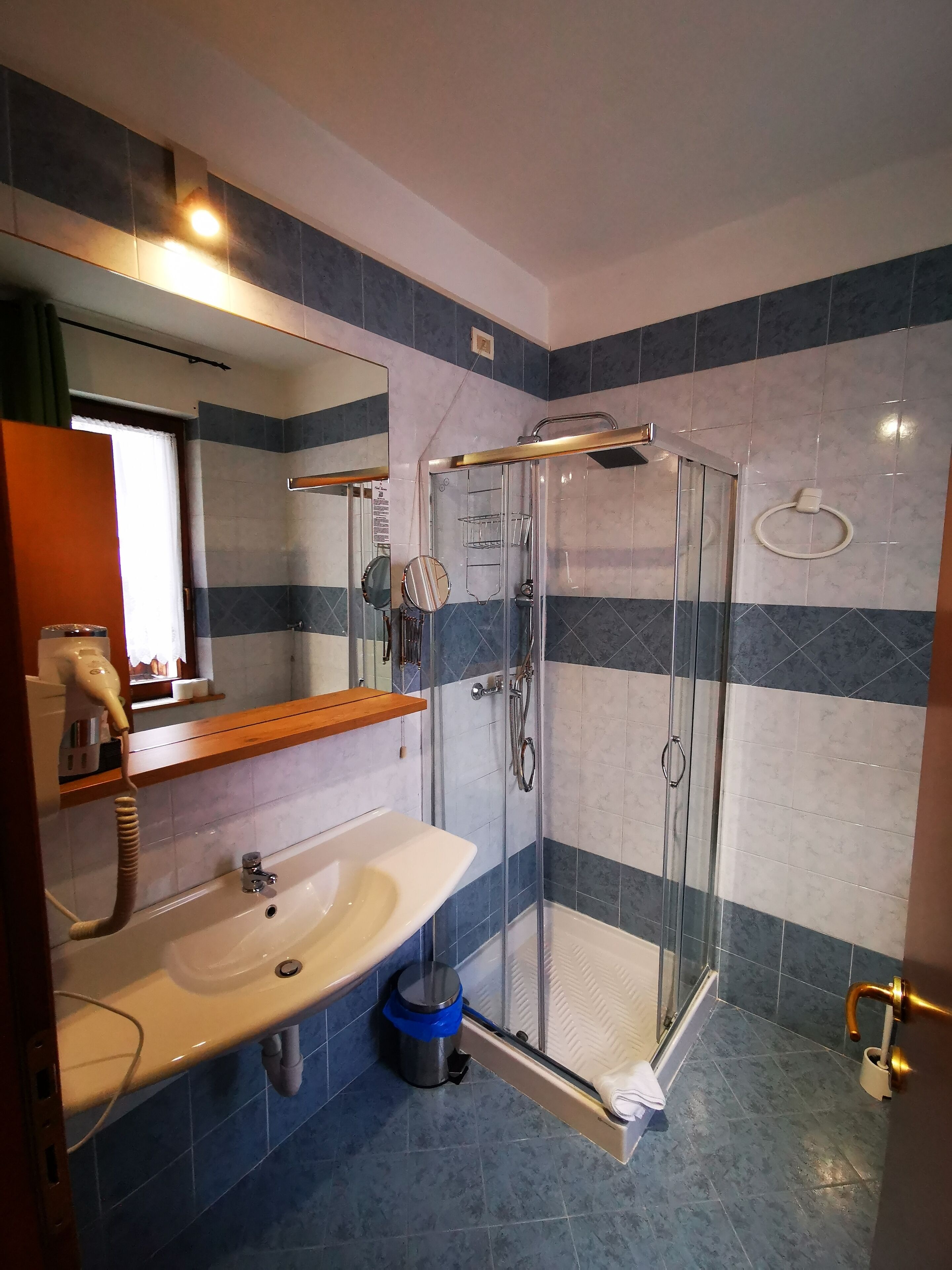 Une salle de bain avec une douche à parois de verre, un lavabo avec un miroir et un porte-serviettes.