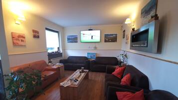 Ein Wohnzimmer mit Couchtisch aus Holz, zwei Sofas, einem Fernseher und an der Wand befestigter Kunst.
