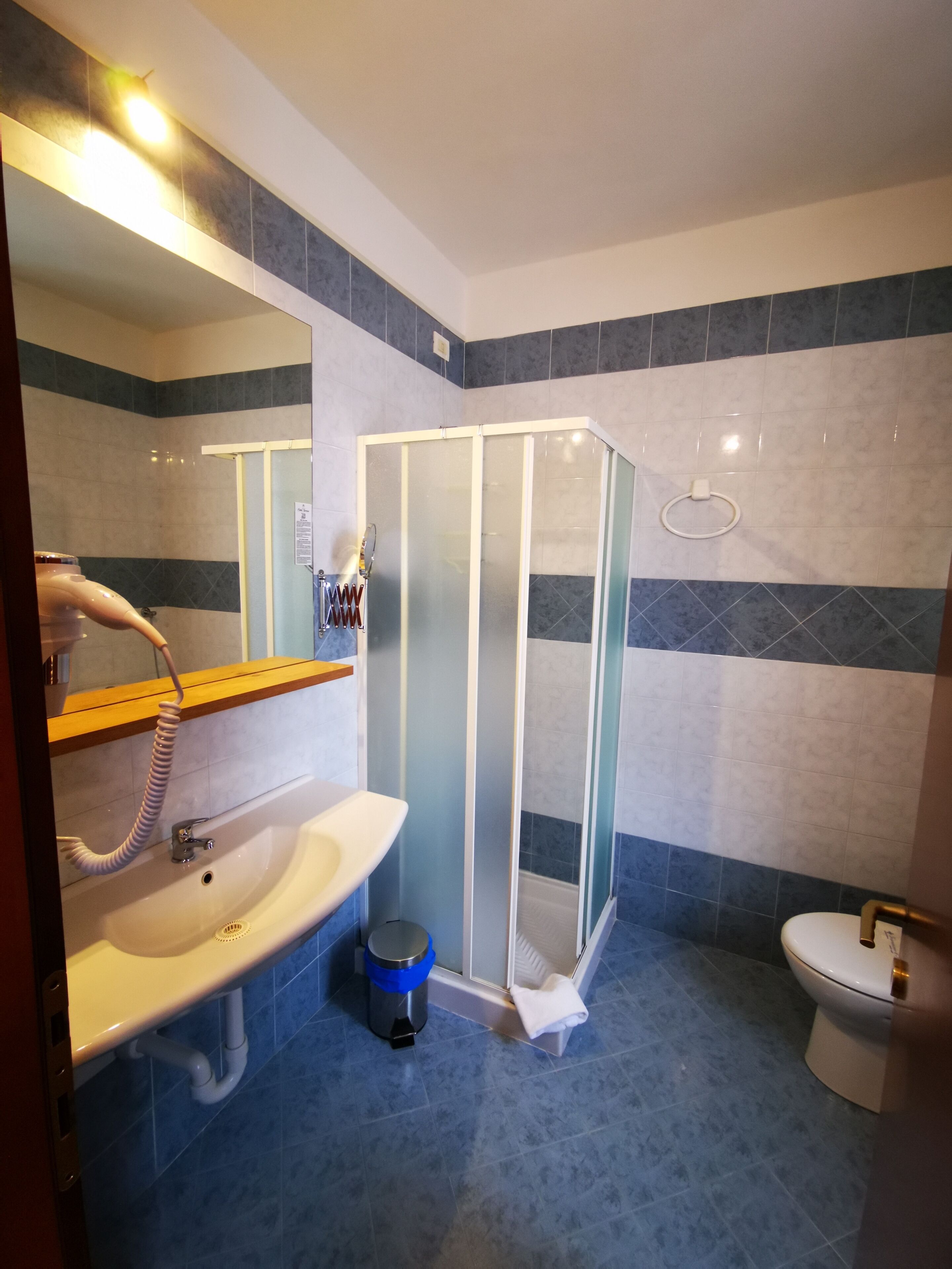 Un baño con cabina de ducha de vidrio, lavamanos con espejo e inodoro.