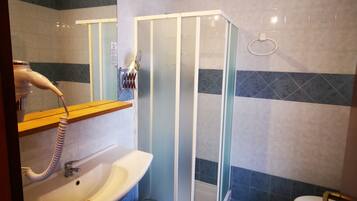 Un baño con cabina de ducha de vidrio, lavamanos con espejo e inodoro.