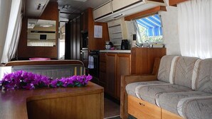 A compact RV interior with a kitchenette, a dining area, and a sleeping berth. - Airstream Paradise (Sainte-Anne)