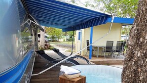 A covered outdoor area with a pool, lounge chairs, and a dining table. - Airstream Paradise (Sainte-Anne)