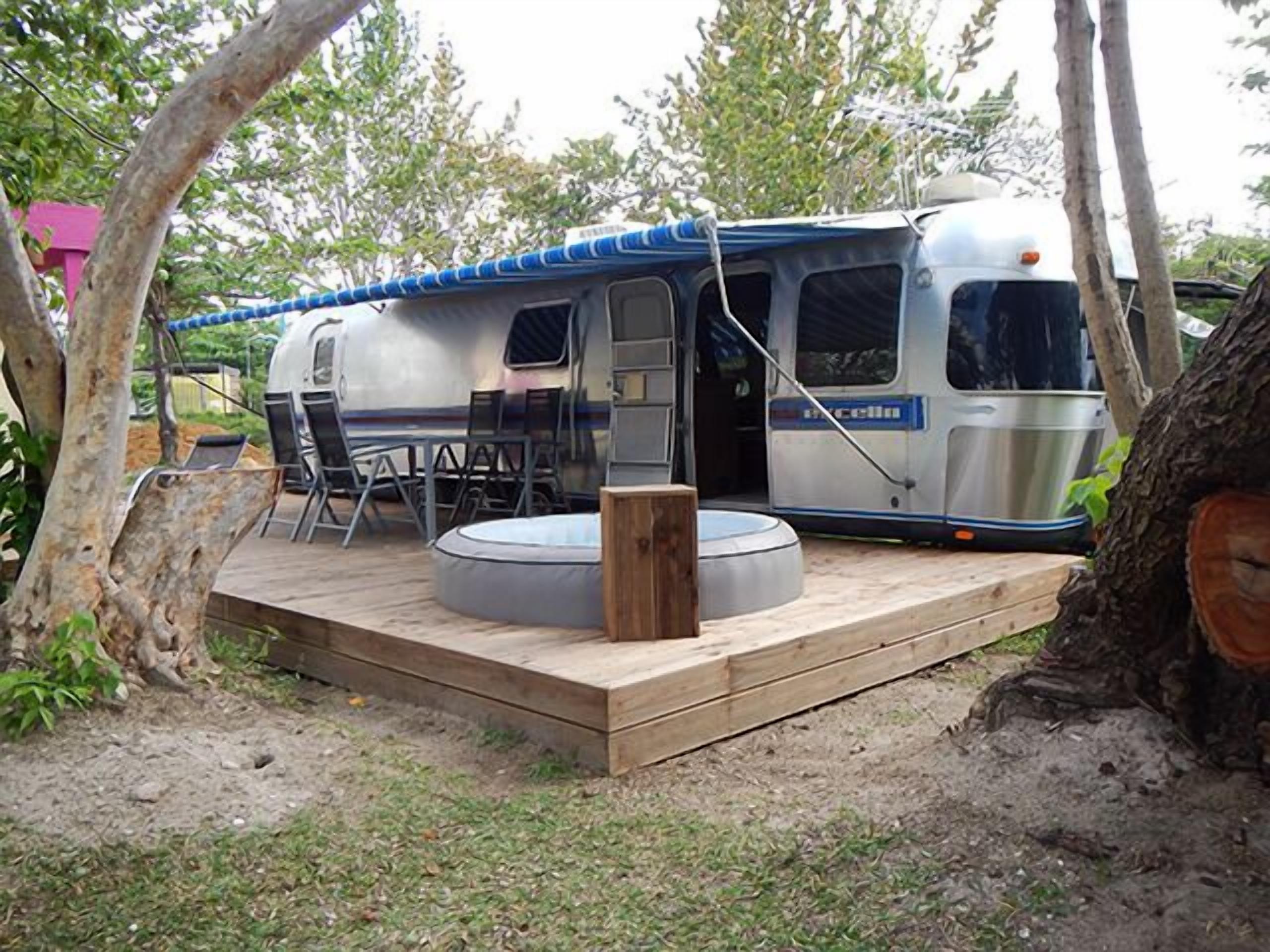 A recreational vehicle with a covered deck, a small outdoor seating area, and a circular water feature.