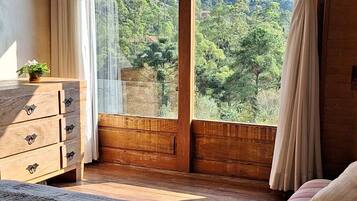 Quarto com uma grande janela, teto de madeira e colcha de cama florida.