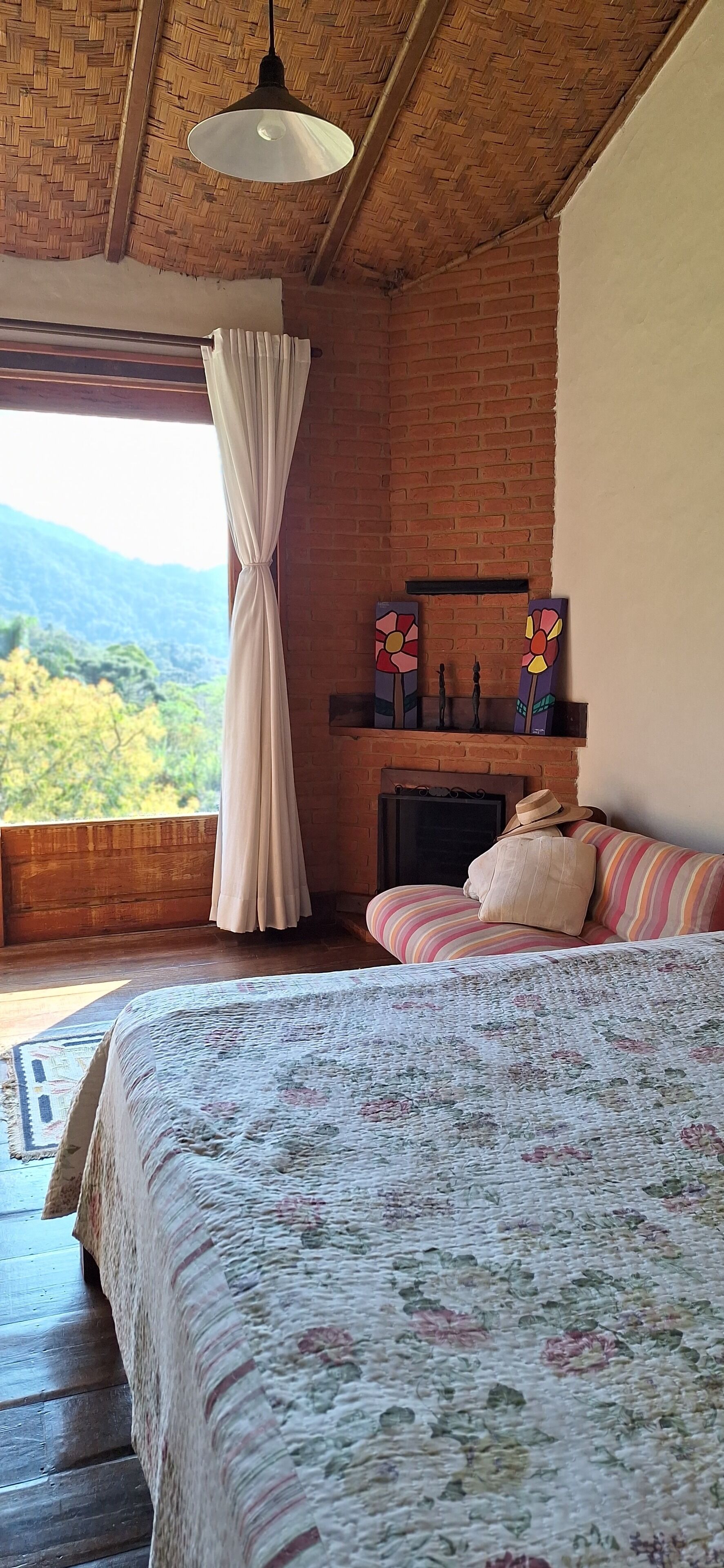 A bedroom with a bed, a fireplace, a view of the mountains, and a hanging light fixture.