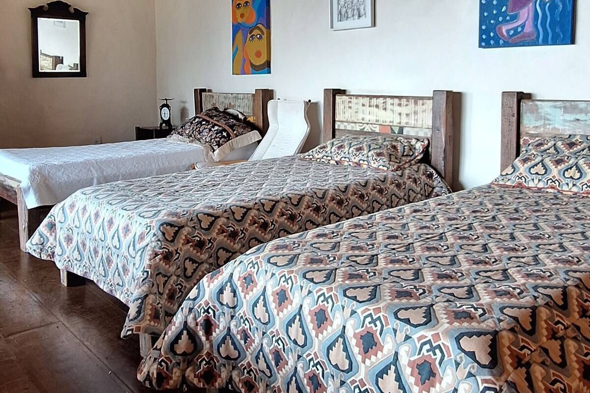 Ein Zimmer mit zwei Betten, Holzbalken an der Decke und Kunstwerken an den Wänden.