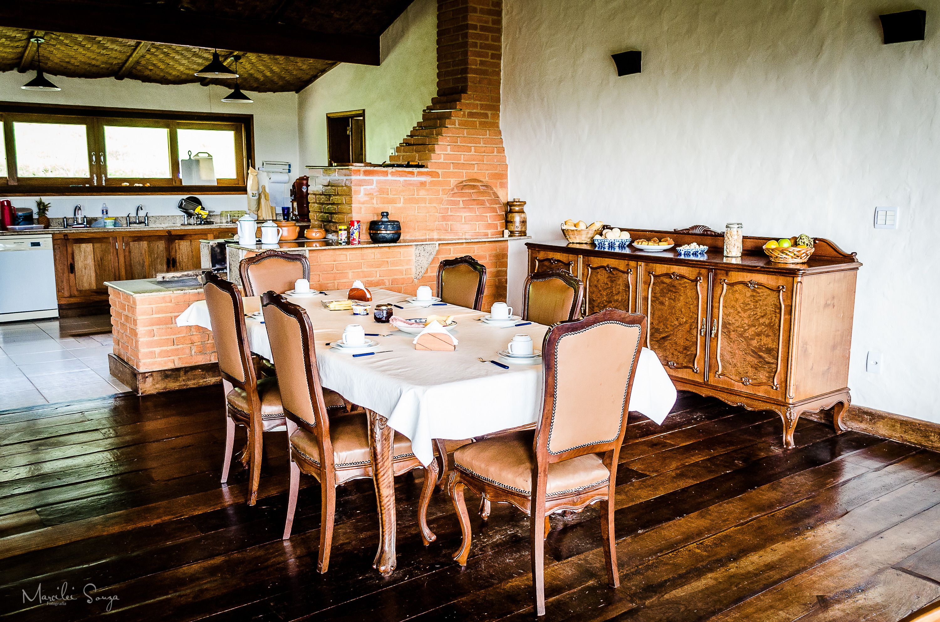 A dining area with a brick fireplace, wooden dining table, and chairs.