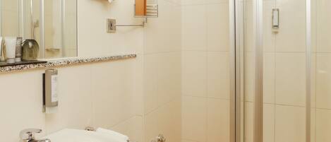Un baño moderno con un lavamanos grande, un espejo, cabina de ducha de vidrio y un perchero para toallas.