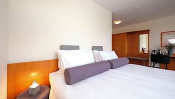 Una habitación de hotel con cama, mesita de noche, lámpara y escritorio con silla.