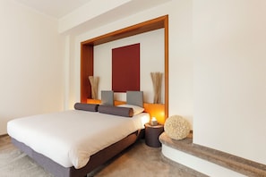 Une chambre d’hôtel moderne avec un grand lit, une tête de lit en bois, une table de chevet et un élément décoratif mural.