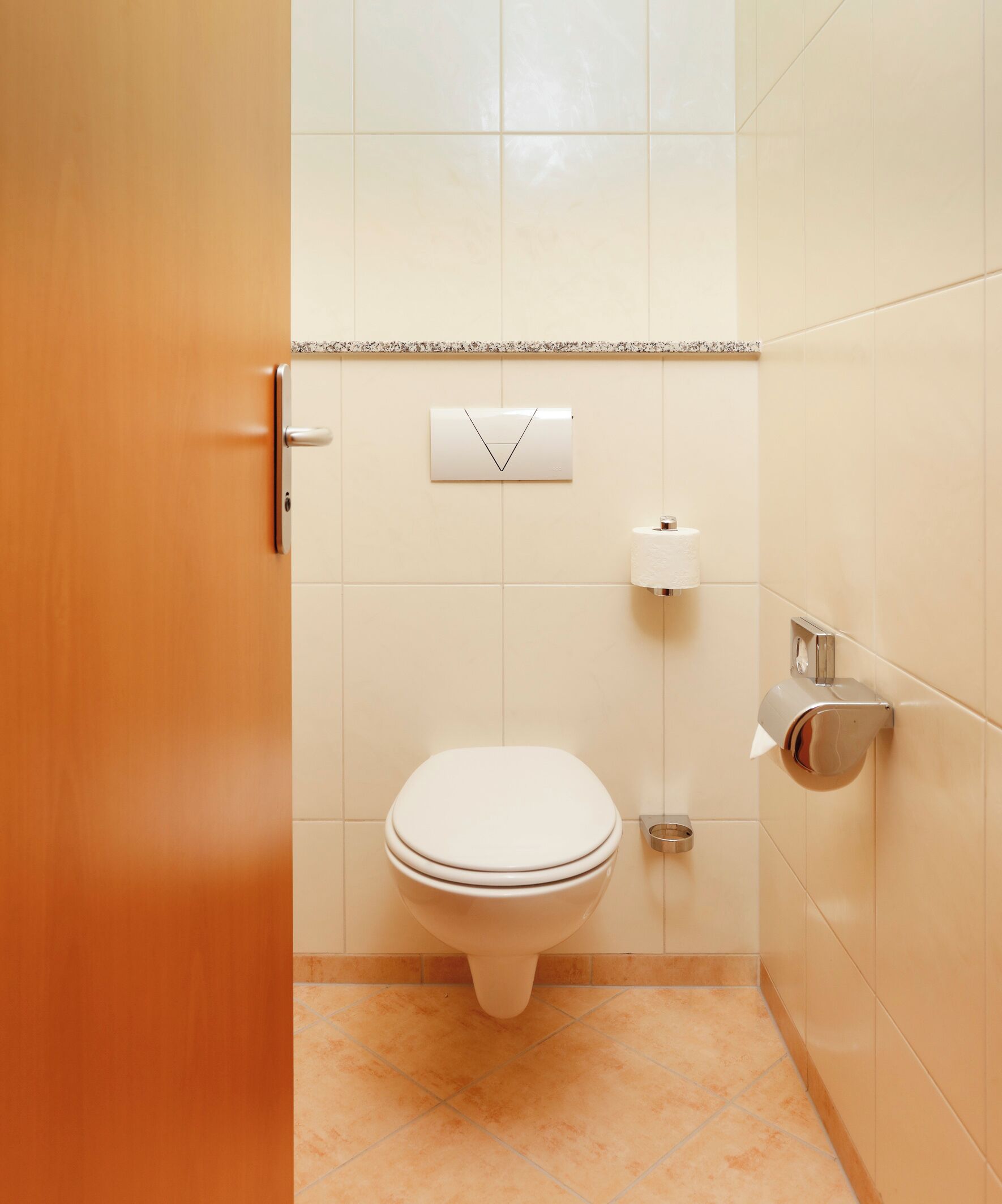 A bathroom with a toilet, a paper towel dispenser, and a soap dispenser.