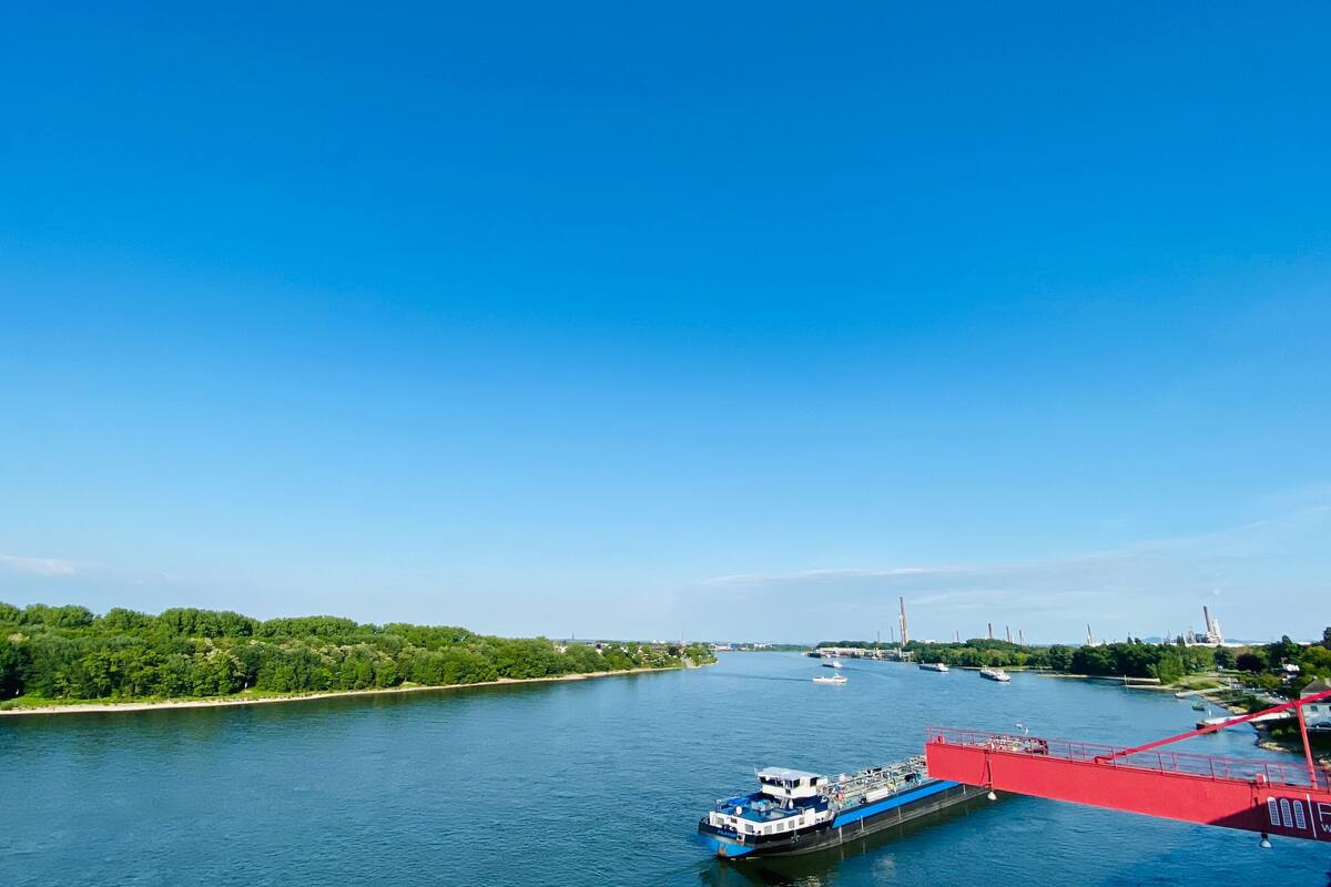 A river with a blue boat and a red bridge.