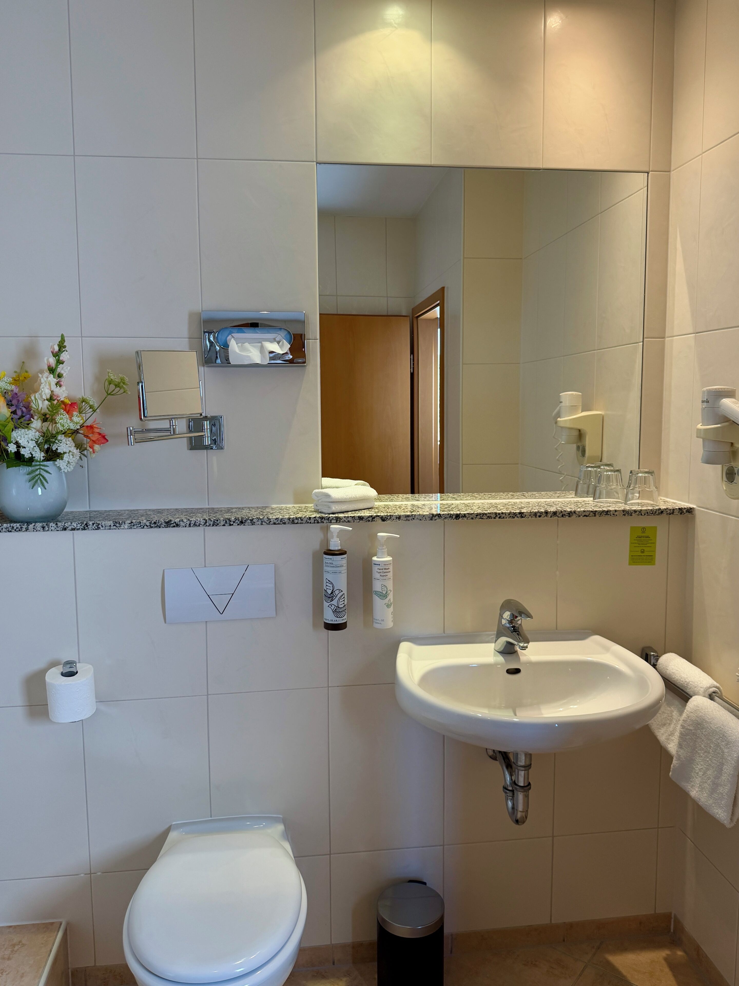 A bathroom with a toilet, sink, mirror, and towel rack.