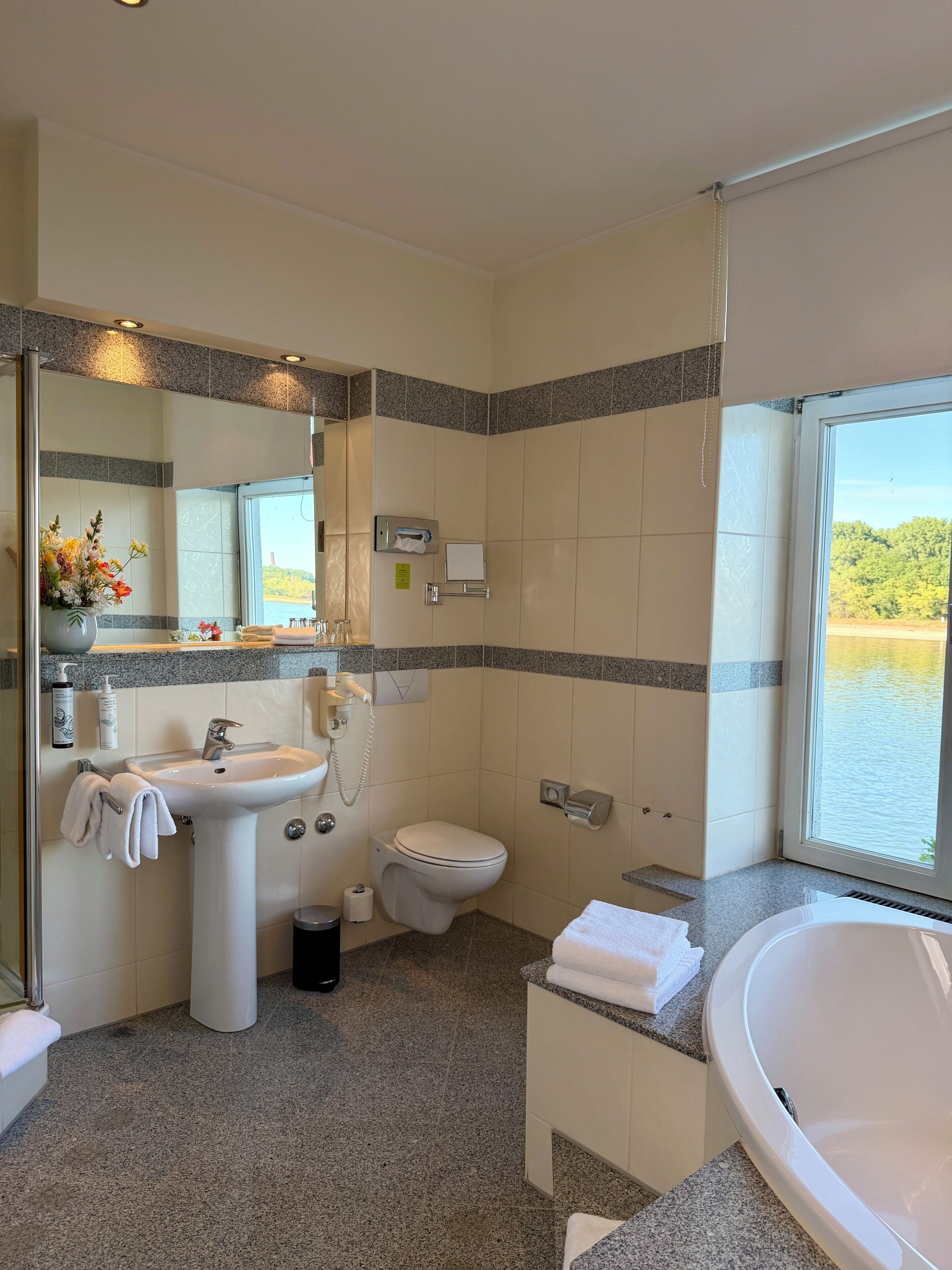 A bathroom with a sink, toilet, and bathtub. There is a window with a view of a body of water.
