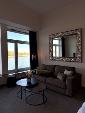 A living room with a sofa, a coffee table, and a large mirror. - Hotel am Rhein - Wesseling (Wesseling)