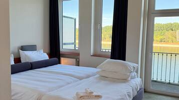 A hotel room with two beds, a view of a lake, and a balcony.