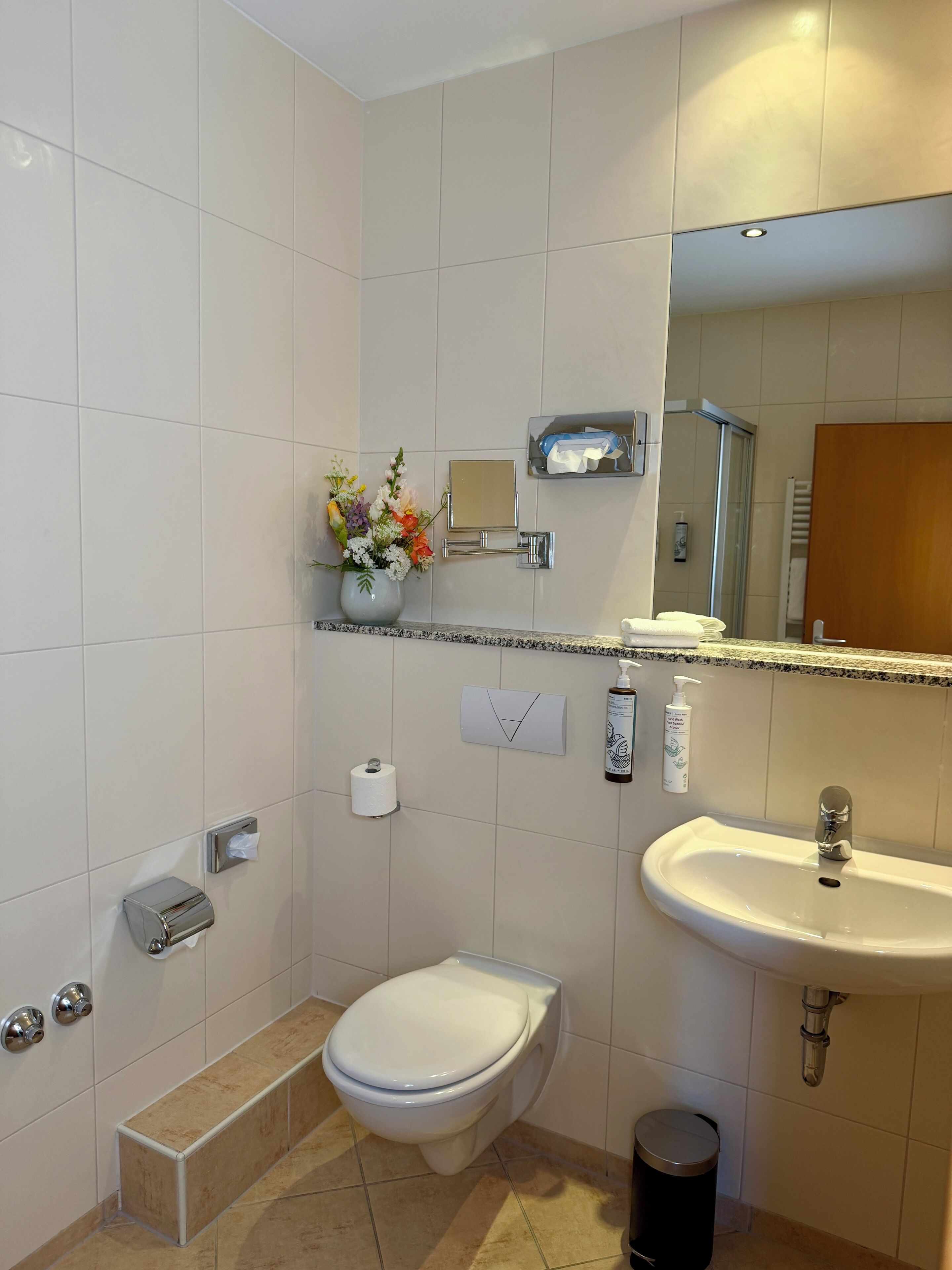 A modern bathroom with a toilet, sink, and shower.
