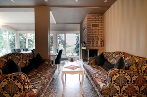 A living room with patterned sofas, a small white table, and a fireplace.
