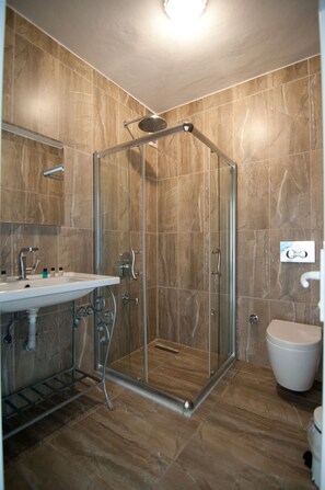 A modern bathroom with a glass-enclosed shower, a sink with a mirror, and a toilet.