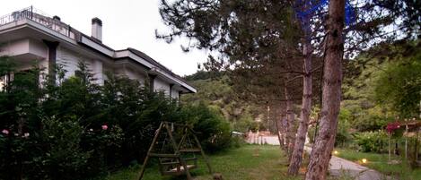 A residential area with a house, a swing set, and a pathway.
