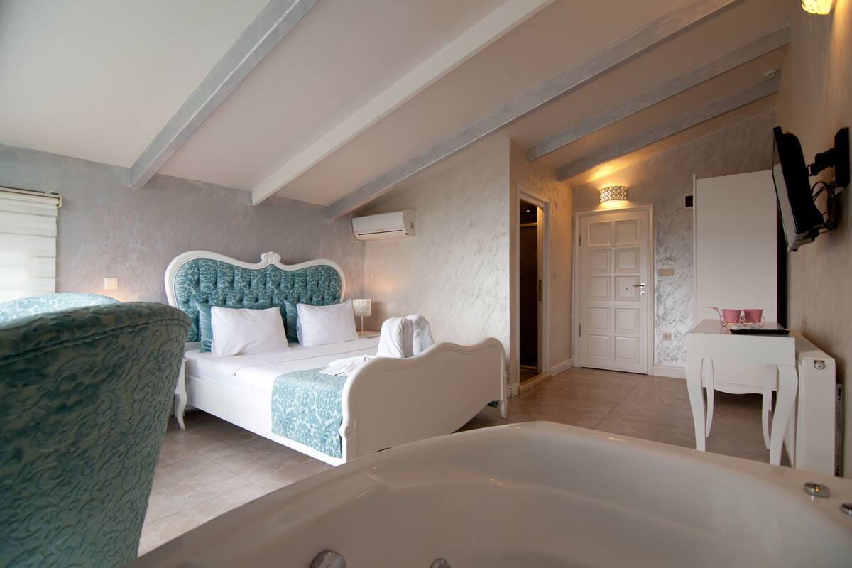 Une chambre à coucher avec un lit, une baignoire, une chaise et une petite table.