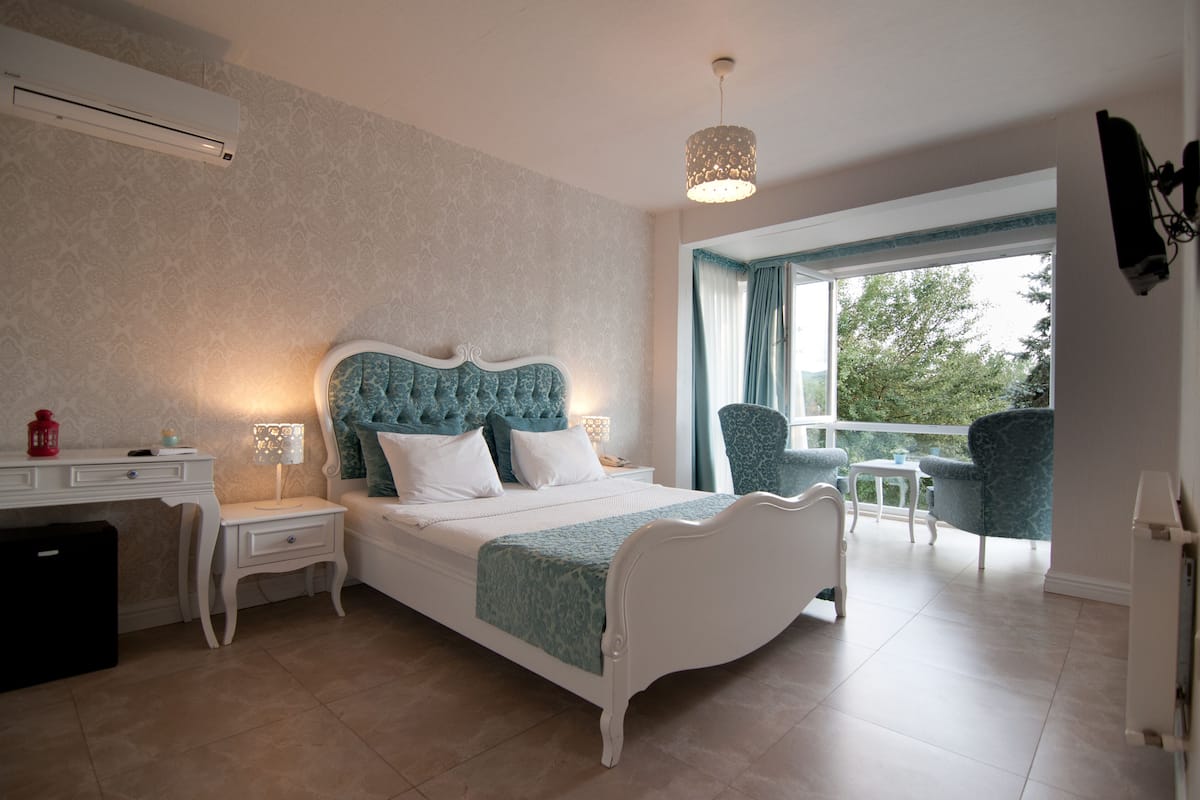 Une chambre à coucher comprenant un lit, des tables de chevet, un bureau, une chaise et un balcon avec vue.