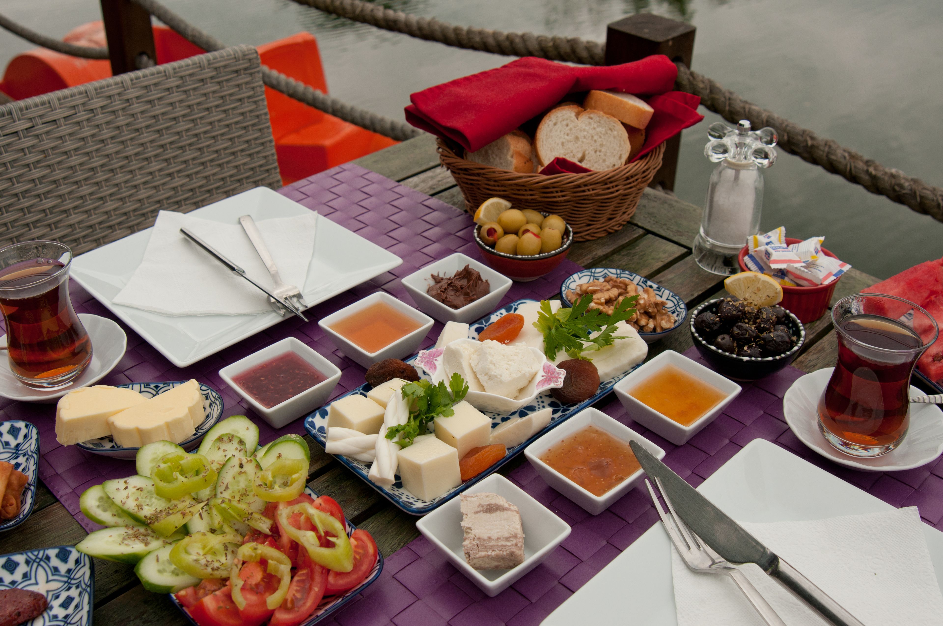 A table set with various cheeses, fruits, and beverages, likely a buffet or meal setup.