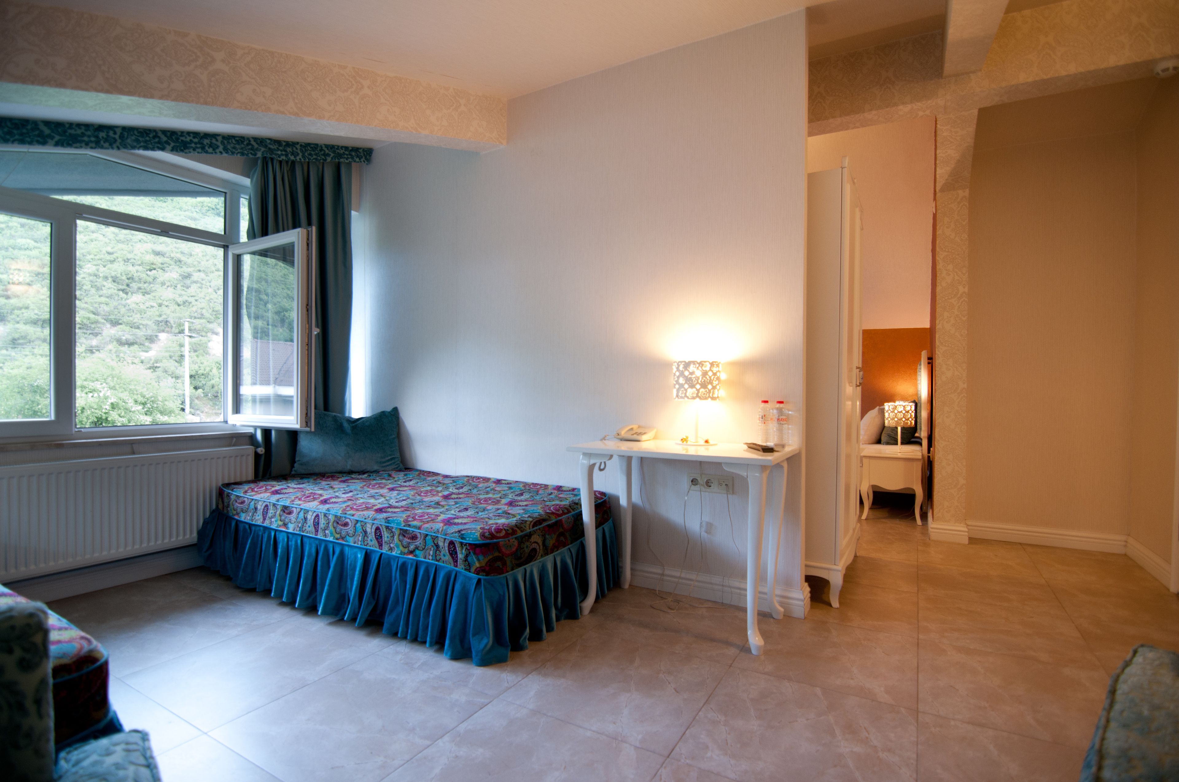 A bedroom with a bed, a desk, and a window.