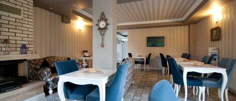 A dining area with blue upholstered chairs, white tables, and a patterned floor.