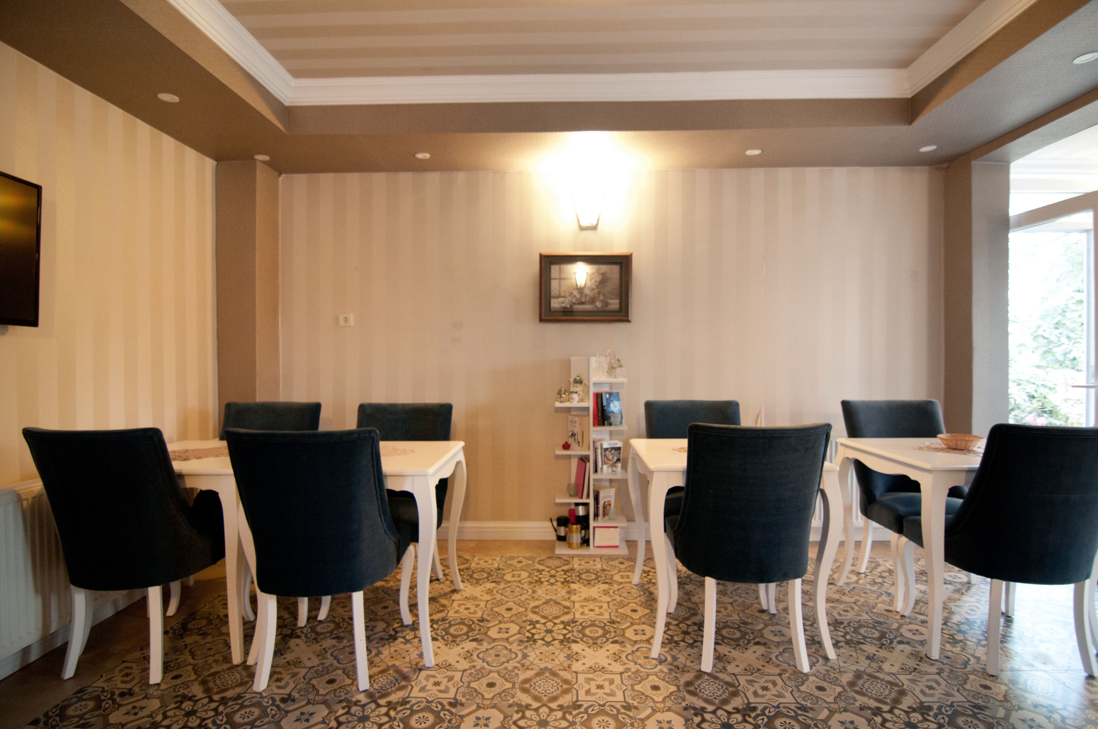 Un comedor con suelo estampado, mesas blancas y sillas negras.