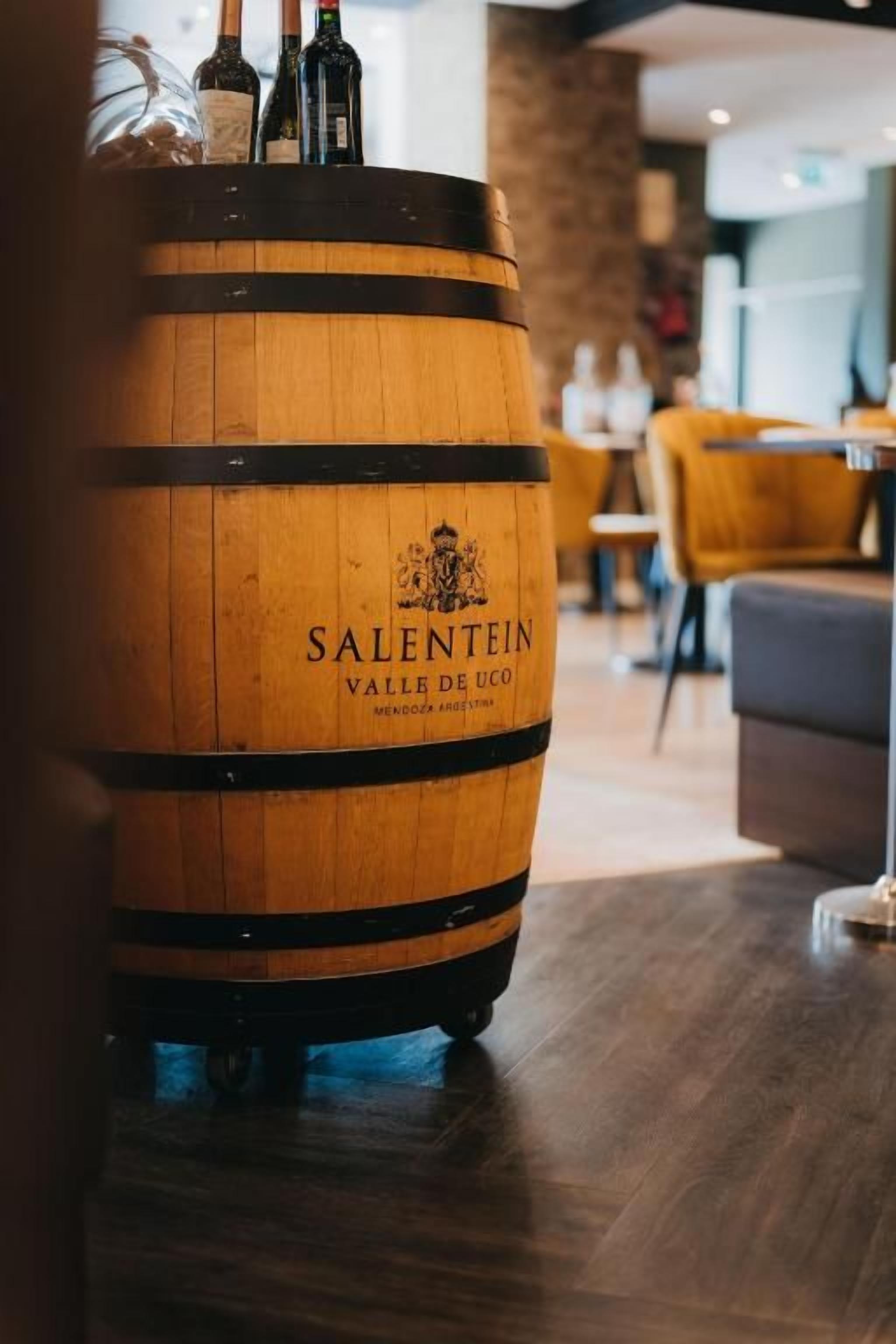 Un barril de madera con la inscripción 'SALENTEIN VALLÉE DE UCO' en un ambiente interior moderno.
