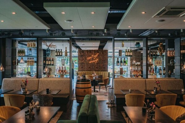 A bar area with seating, a neon sign, and shelves of bottles.