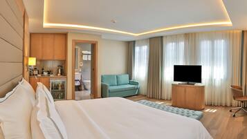 A hotel room with a bed, a television, a seating area, and a kitchenette.