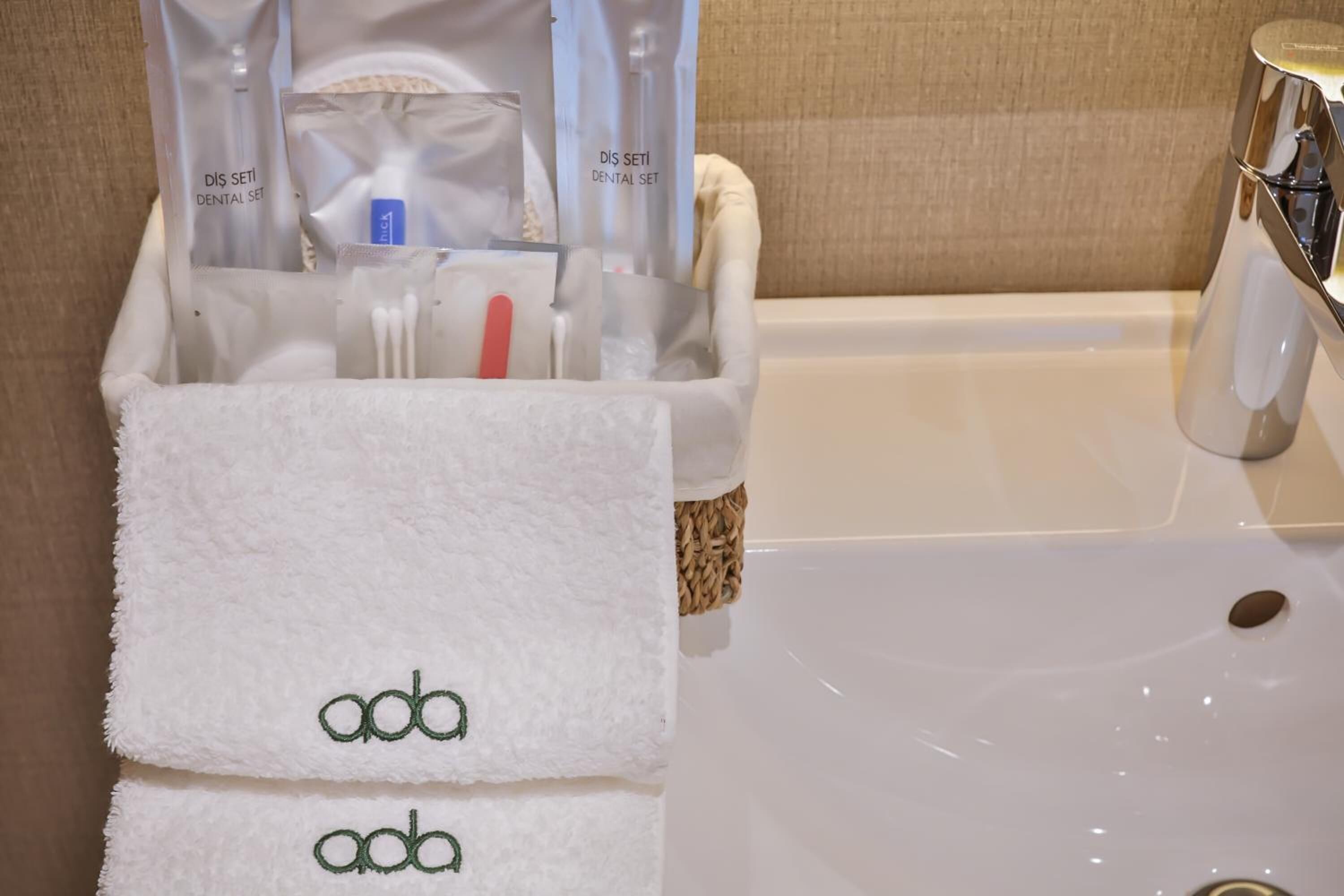 A bathroom with a white sink, a towel rack with two towels, and a dental care kit in a transparent container.
