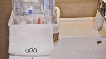 A bathroom with a white sink, a towel rack with two towels, and a dental care kit in a transparent container.